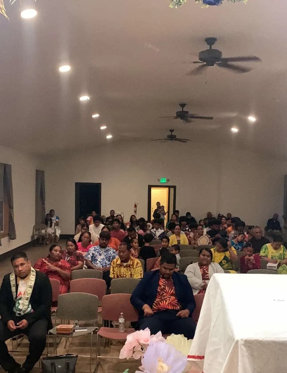 The congregation seated for a Sunday service, filling rows of chairs in the church hall.